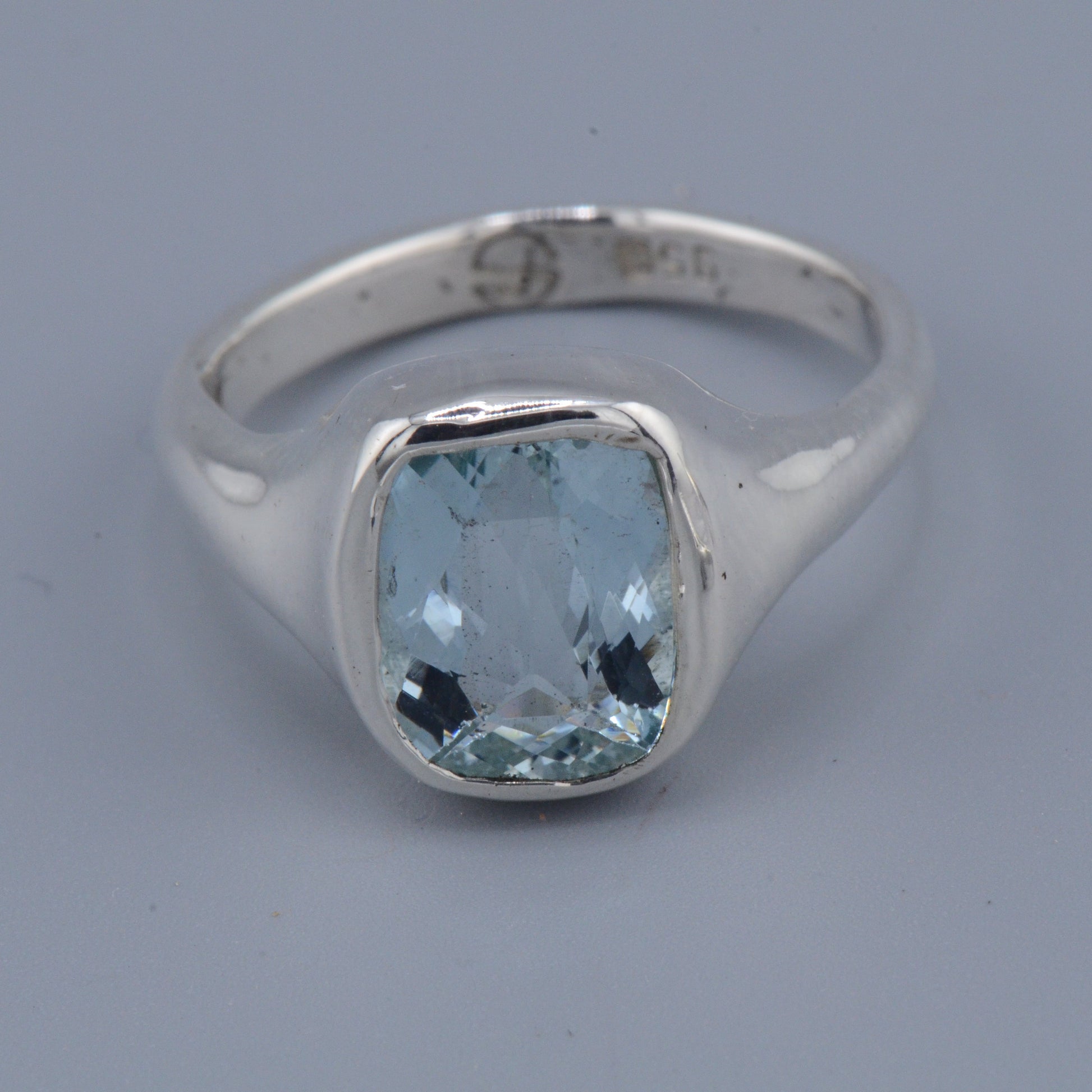 Silver ring with a blue gemstone on a gray background