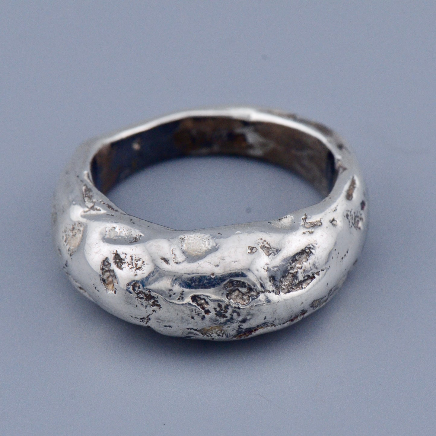 Silver ring with a textured surface on a gray background