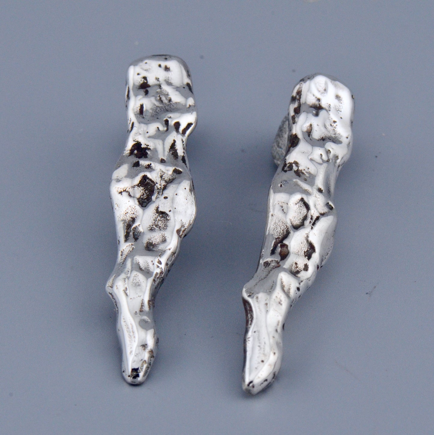 Pair of silver earrings on a gray background