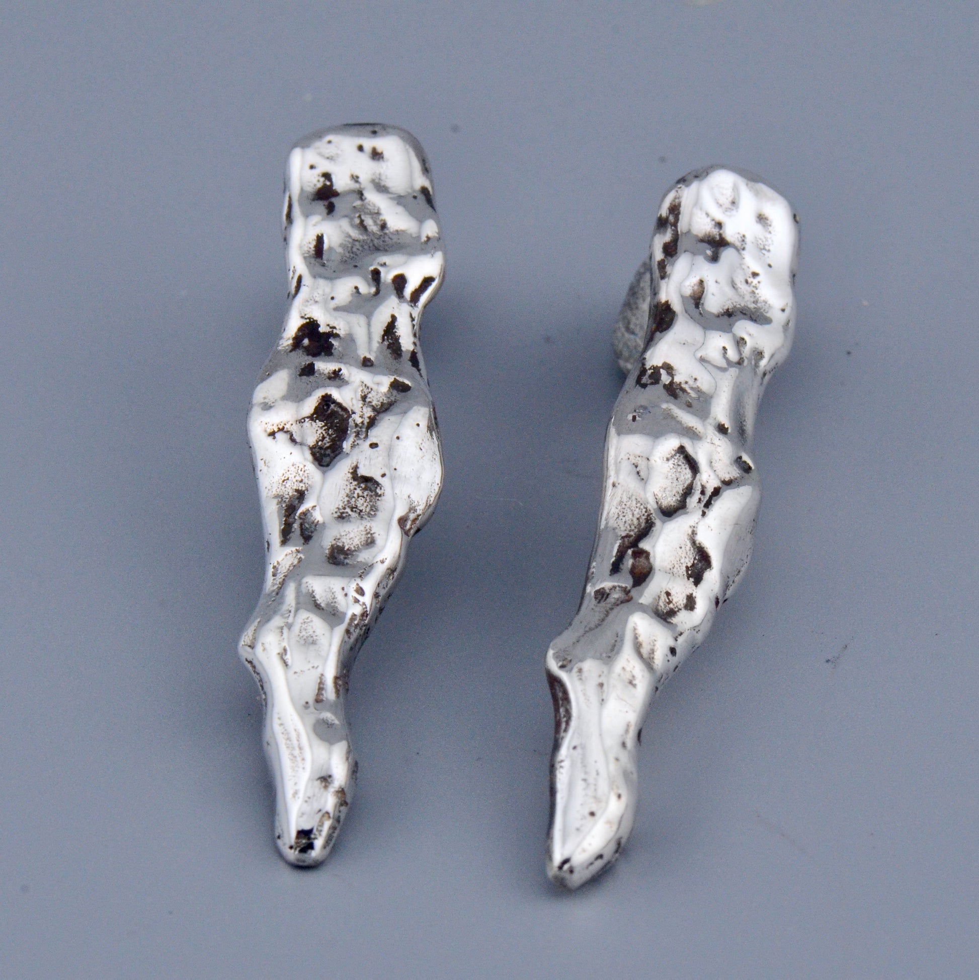 Pair of silver earrings on a gray background