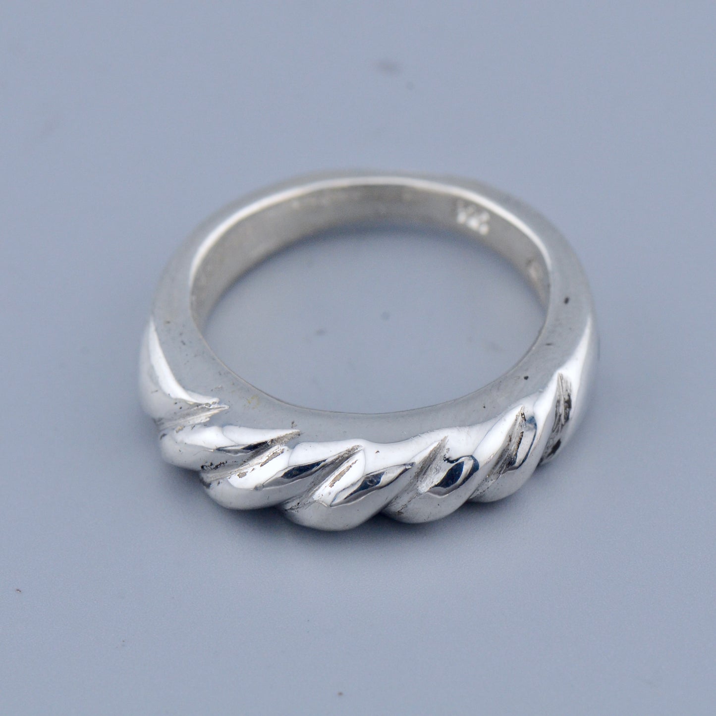 Silver twisted ring on a gray background