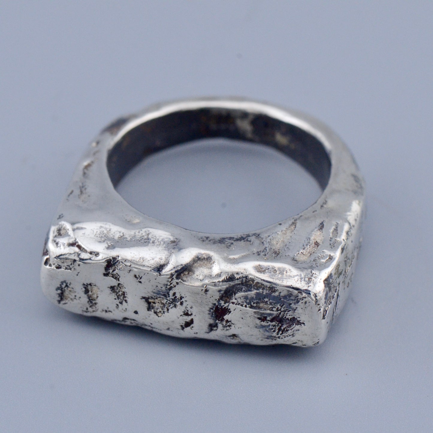 Silver square ring with a textured surface on a gray background