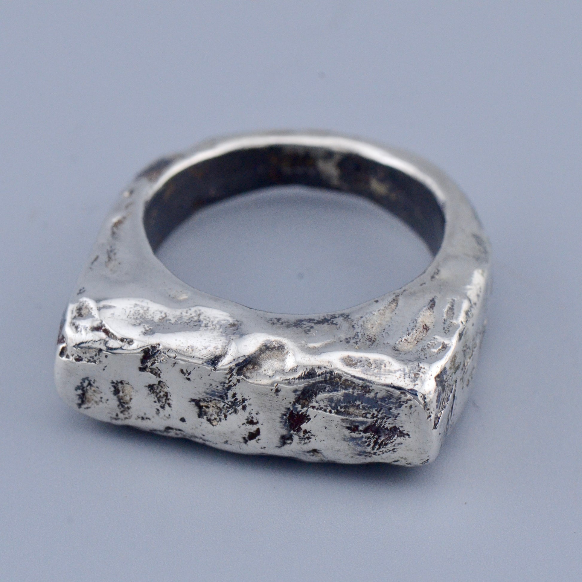 Silver square ring with a textured surface on a gray background