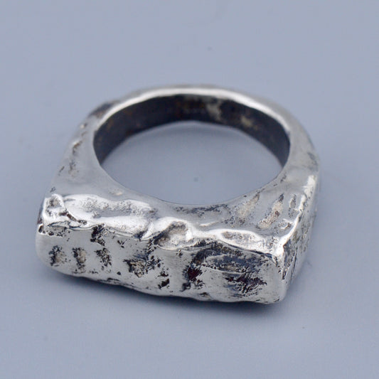 Silver square ring with a textured surface on a gray background