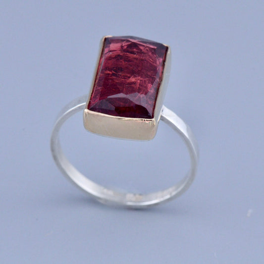 Silver ring with a red gemstone on a light blue background