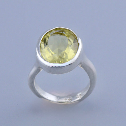Silver ring with a yellow gemstone on a light gray background