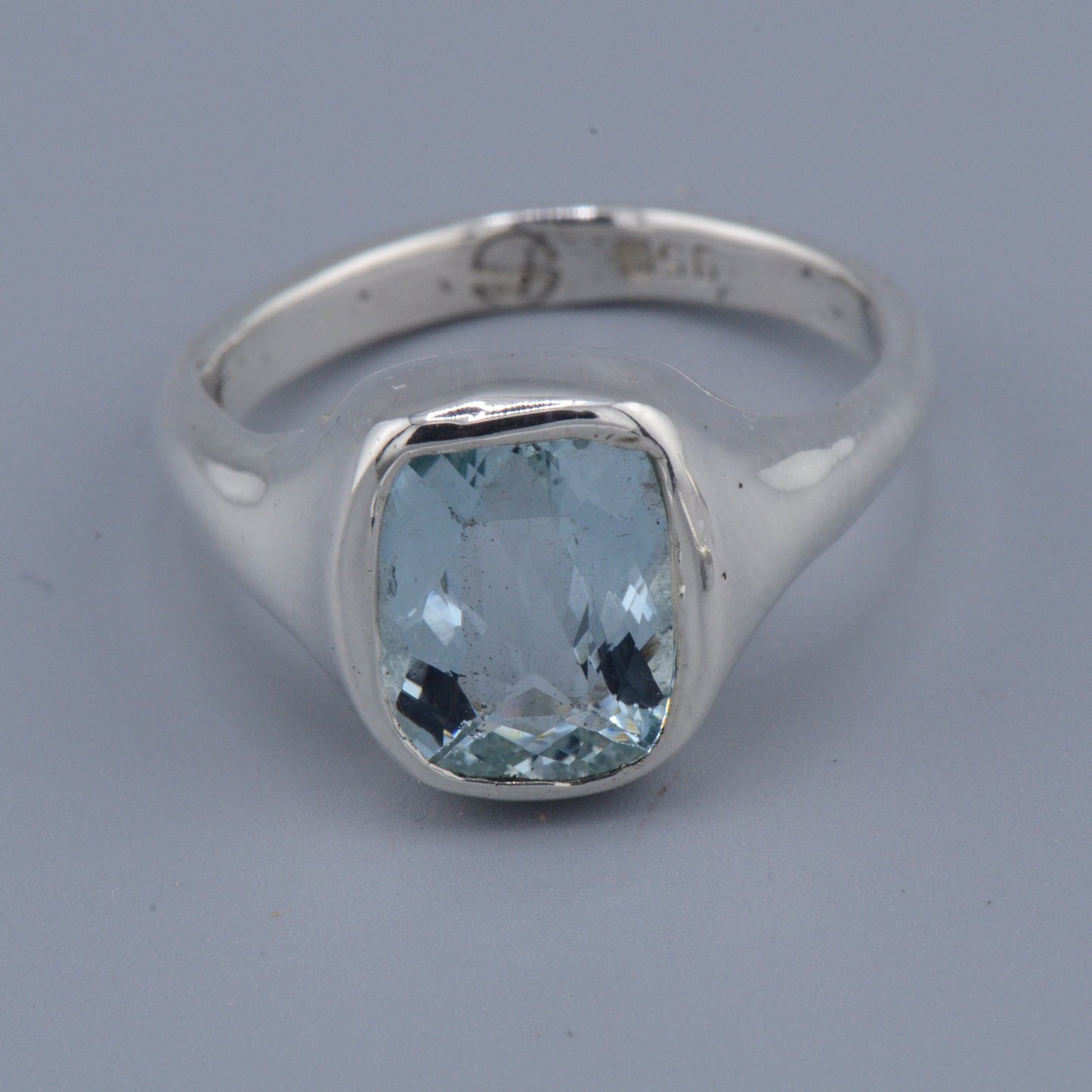 Silver ring with a blue gemstone on a gray background