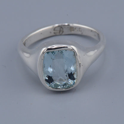 Silver ring with a blue gemstone on a gray background
