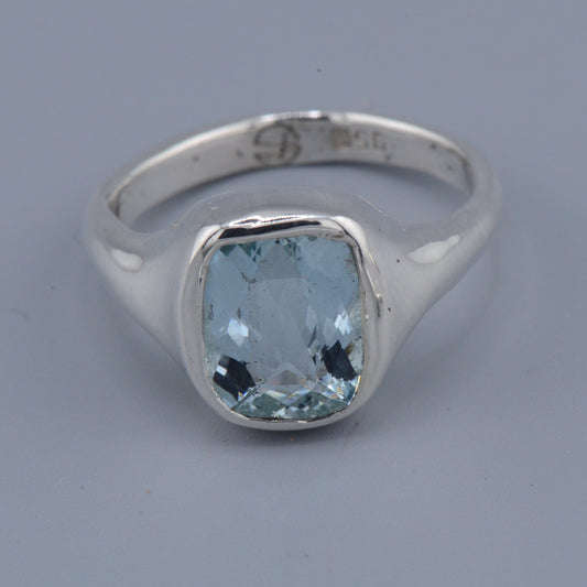 Silver ring with a blue gemstone on a gray background