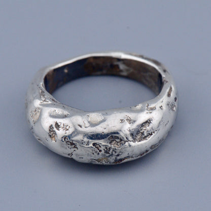 Silver ring with a textured surface on a gray background