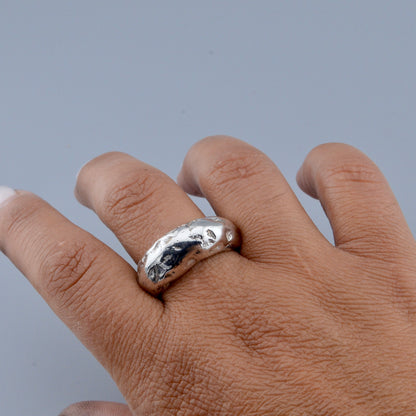 Hand wearing a silver ring on a gray background