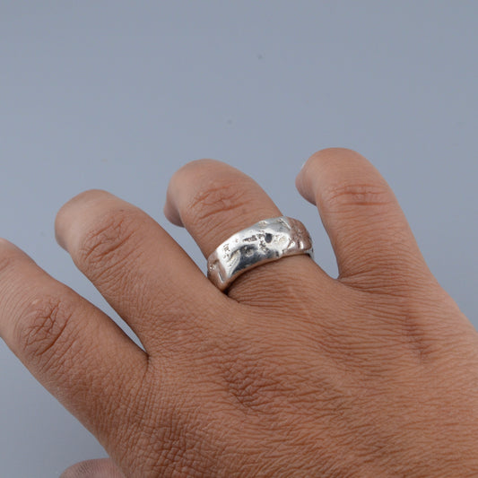 Hand wearing a silver ring on a plain background