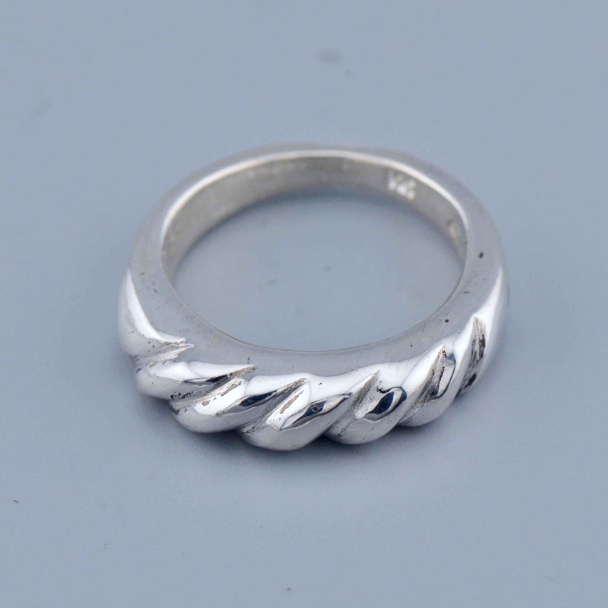 Silver twisted ring on a gray background