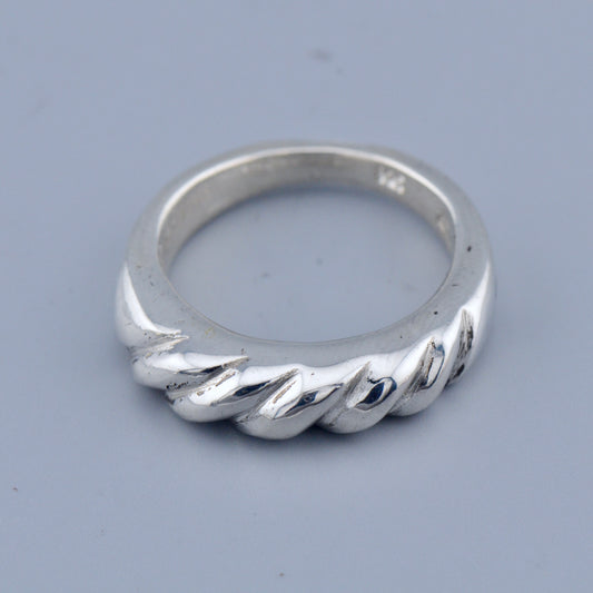 Silver twisted ring on a gray background