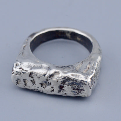 Silver square ring with a textured surface on a gray background